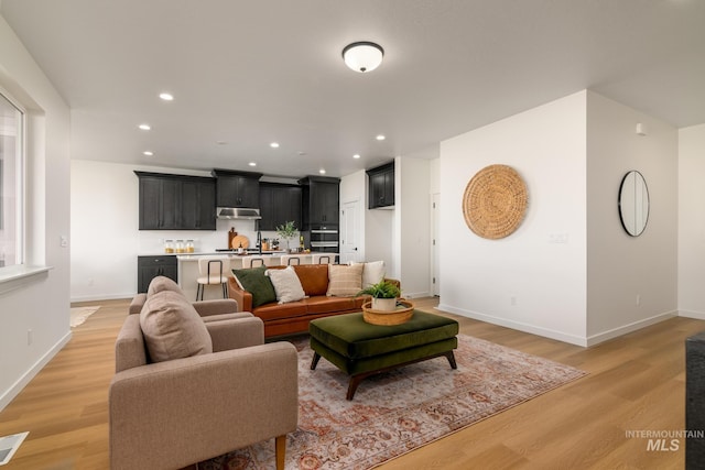 living room featuring baseboards, recessed lighting, and light wood finished floors