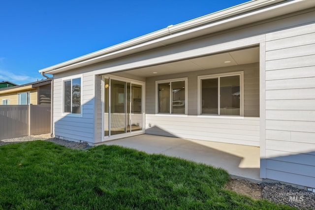 rear view of property with fence, a patio area, and a lawn