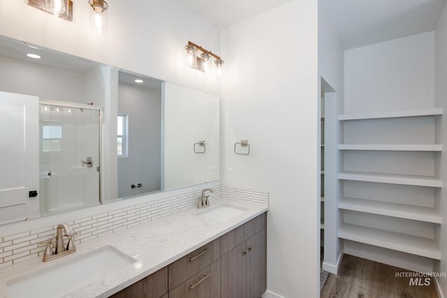 bathroom with hardwood / wood-style flooring, vanity, an enclosed shower, and decorative backsplash