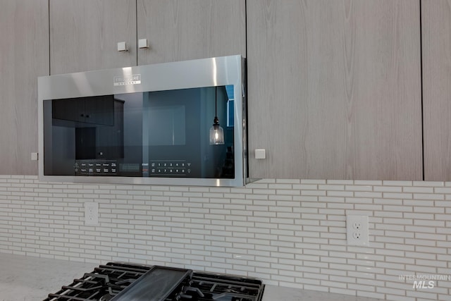 details featuring tasteful backsplash, stovetop, light brown cabinets, and light stone counters