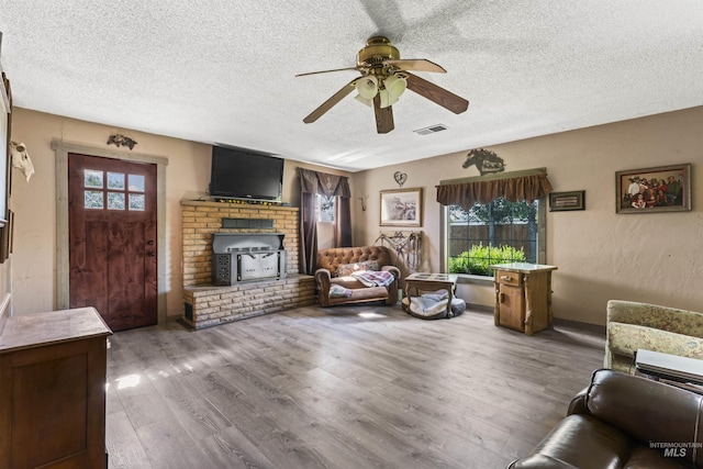 19550 Whitecap Ct, Wilder, ID 83676 - living room featuring ceiling fan, a fireplace, a textured ceiling, healthy amount of natural light, and wood finished floors
