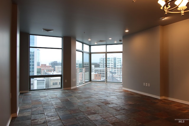 unfurnished room with expansive windows and an inviting chandelier