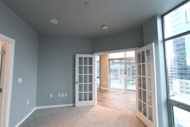 empty room with french doors, light colored carpet, and a healthy amount of sunlight