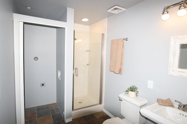 bathroom featuring sink, a shower with shower door, and toilet