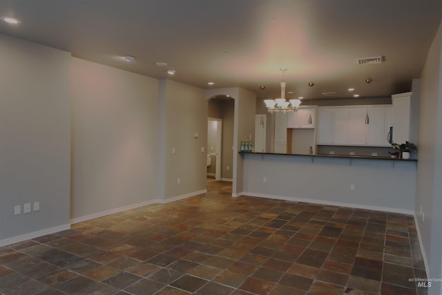 kitchen featuring kitchen peninsula, white cabinetry, decorative light fixtures, and an inviting chandelier