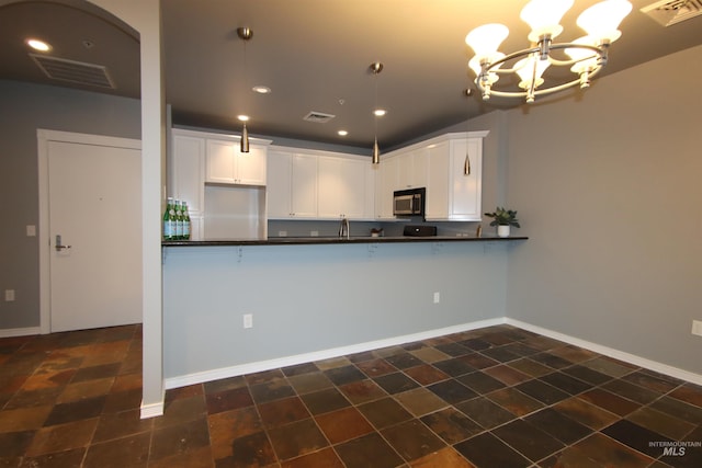 kitchen featuring a notable chandelier, white cabinetry, hanging light fixtures, and kitchen peninsula