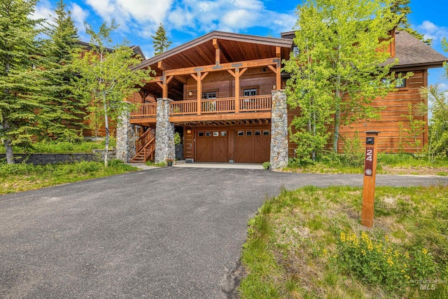 view of front facade featuring an attached garage, stone siding, and driveway