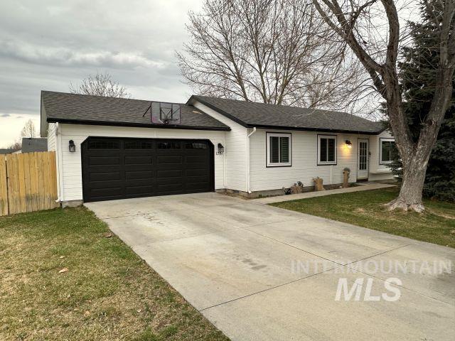 single story home featuring a front lawn, concrete driveway, a garage, and fence