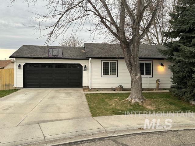 single story home featuring a shingled roof, fence, concrete driveway, a front yard, and a garage