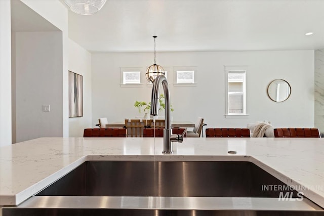 interior details featuring pendant lighting, light stone counters, and a sink