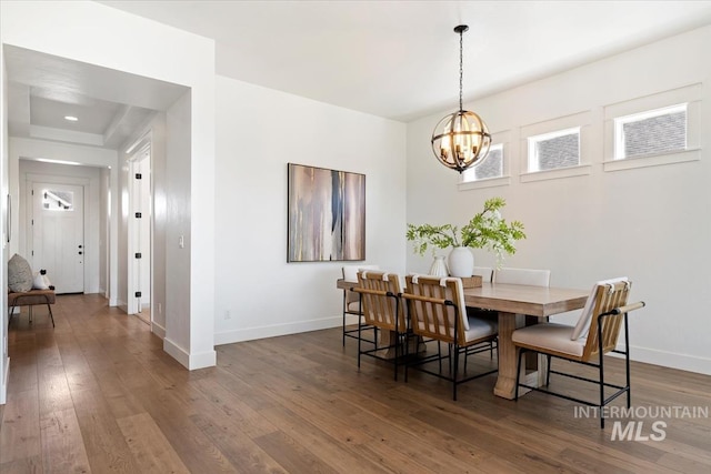 dining area with dark wood-style flooring, baseboards, and a notable chandelier