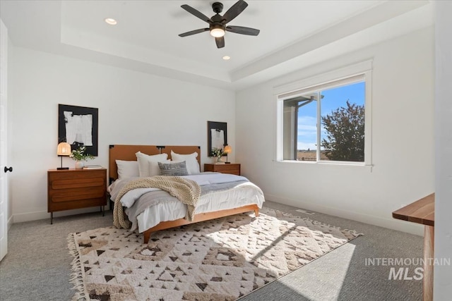 carpeted bedroom featuring baseboards, a raised ceiling, recessed lighting, and a ceiling fan