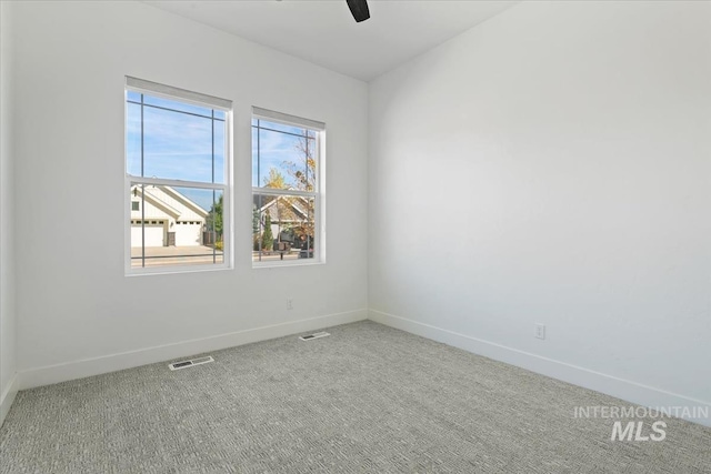 carpeted empty room featuring visible vents, baseboards, and ceiling fan