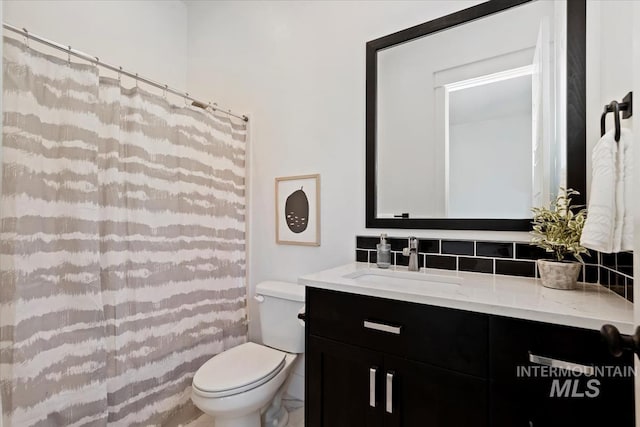full bath with toilet, decorative backsplash, curtained shower, and vanity