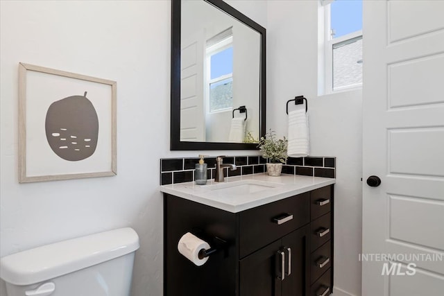 bathroom featuring toilet, vanity, decorative backsplash, and plenty of natural light