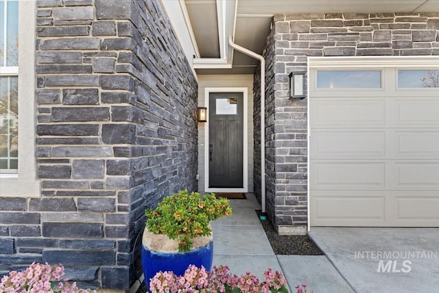 entrance to property with a garage and stone siding