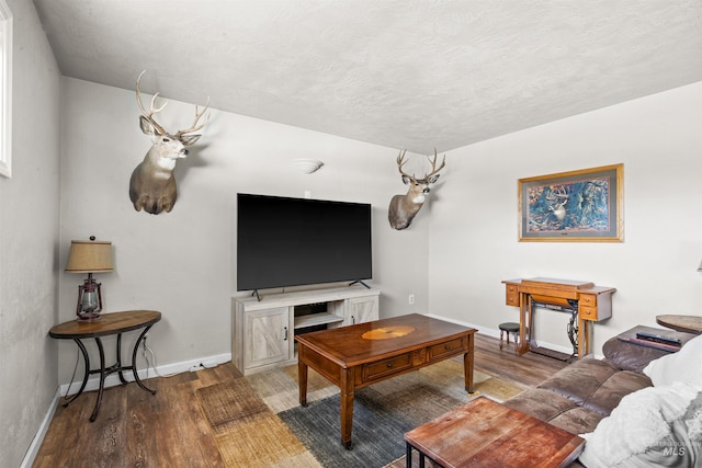 living area featuring a textured ceiling, baseboards, and wood finished floors