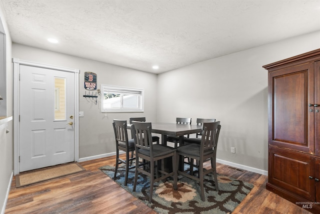 dining room featuring dark wood-style floors, a textured ceiling, recessed lighting, and baseboards