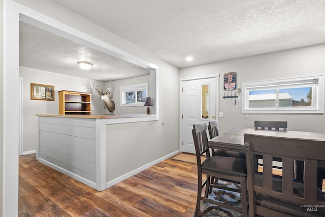 dining room with a textured ceiling, wood finished floors, and baseboards