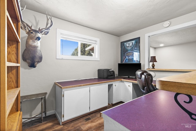 home office featuring a textured ceiling, dark wood-style flooring, built in study area, and visible vents