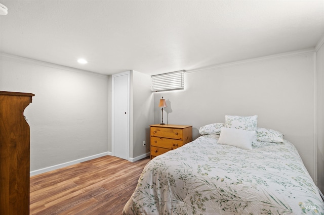 bedroom with crown molding, baseboards, and wood finished floors