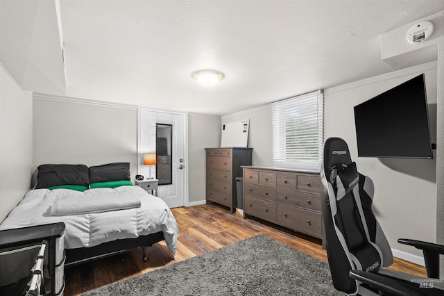 bedroom featuring a textured ceiling, wood finished floors, and baseboards