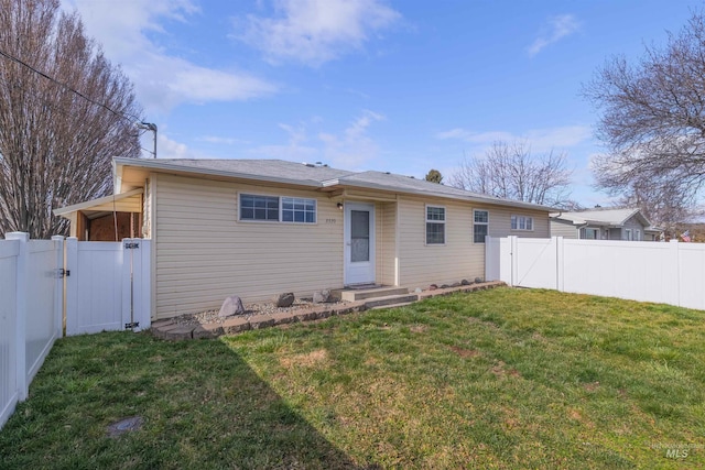 rear view of property with a fenced backyard, a gate, and a lawn