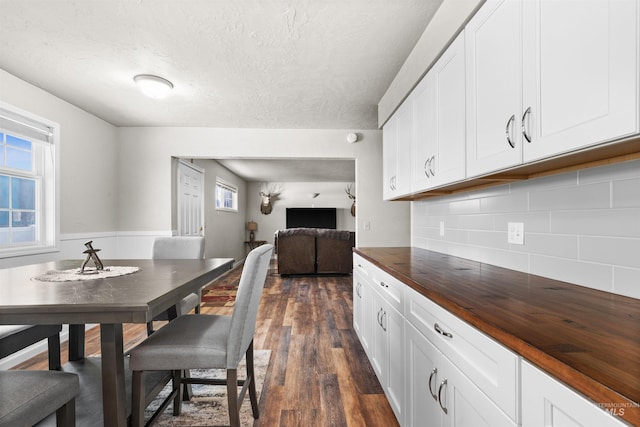 dining space with a textured ceiling and dark wood finished floors