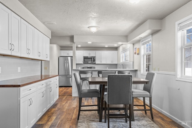 dining space with a healthy amount of sunlight, dark wood-style flooring, and wainscoting