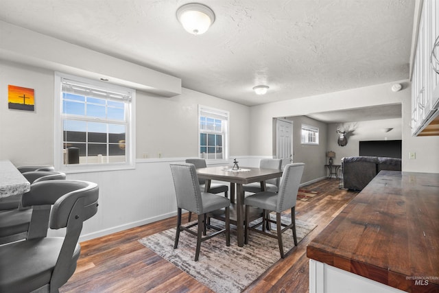 dining room featuring a textured ceiling, baseboards, and dark wood-style flooring