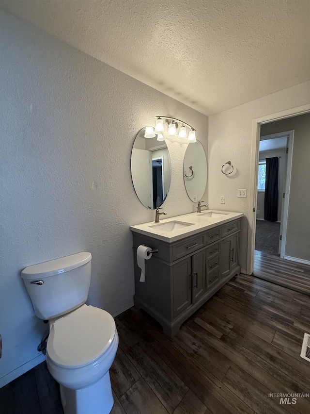 10342 W Ardyce St, Boise, ID 83704 - bathroom with wood finished floors, a textured ceiling, toilet, double vanity, and a textured wall