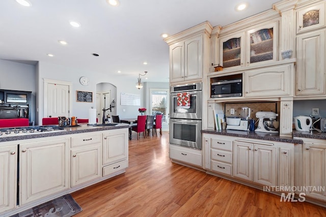 kitchen featuring sink, decorative backsplash, light hardwood / wood-style floors, stainless steel appliances, and cream cabinets