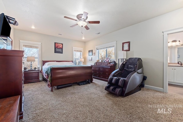 carpeted bedroom with multiple windows, sink, connected bathroom, and ceiling fan