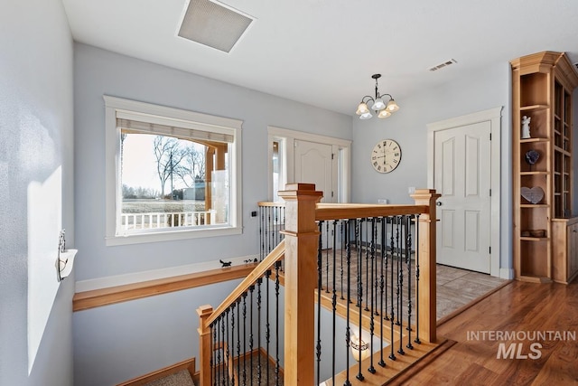 hallway with an inviting chandelier and light hardwood / wood-style floors