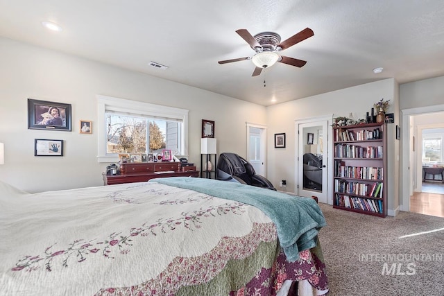 carpeted bedroom featuring multiple windows and ceiling fan