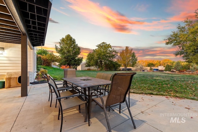 patio terrace at dusk featuring a yard