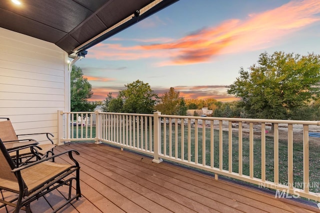 deck at dusk featuring a yard