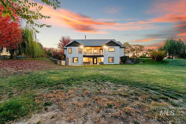 back house at dusk featuring a lawn