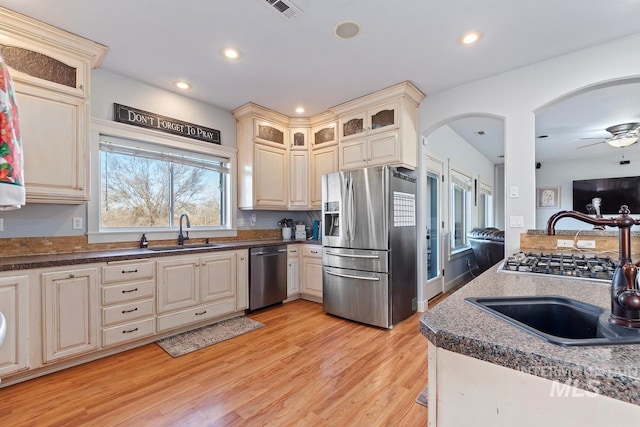 kitchen featuring appliances with stainless steel finishes, sink, cream cabinets, and light wood-type flooring