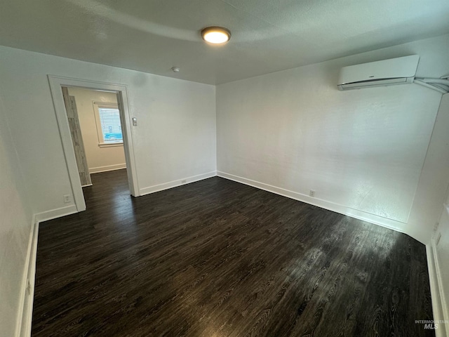 spare room featuring dark hardwood / wood-style floors and a wall unit AC