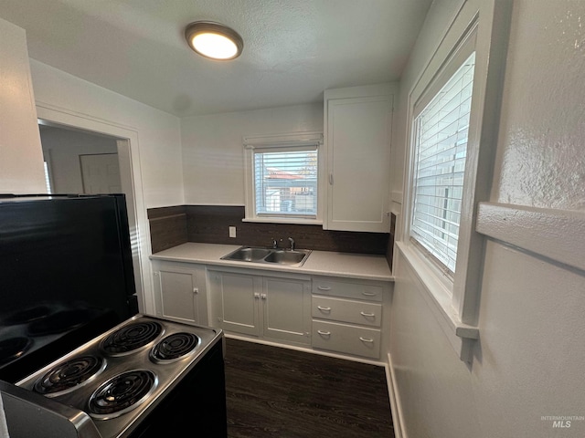 kitchen featuring stove, sink, dark hardwood / wood-style floors, decorative backsplash, and white cabinetry