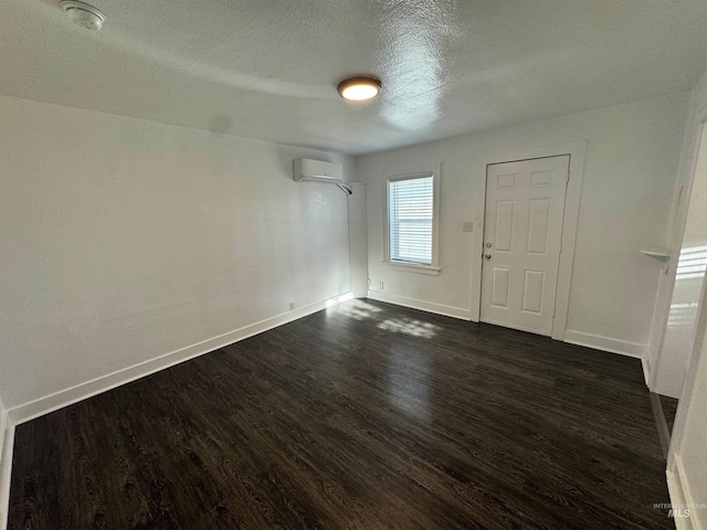 spare room with a textured ceiling, dark hardwood / wood-style floors, and a wall mounted air conditioner