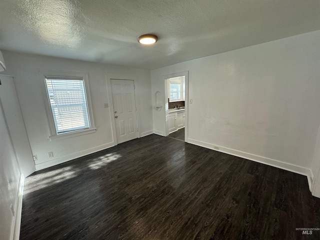 spare room featuring a textured ceiling and dark hardwood / wood-style floors