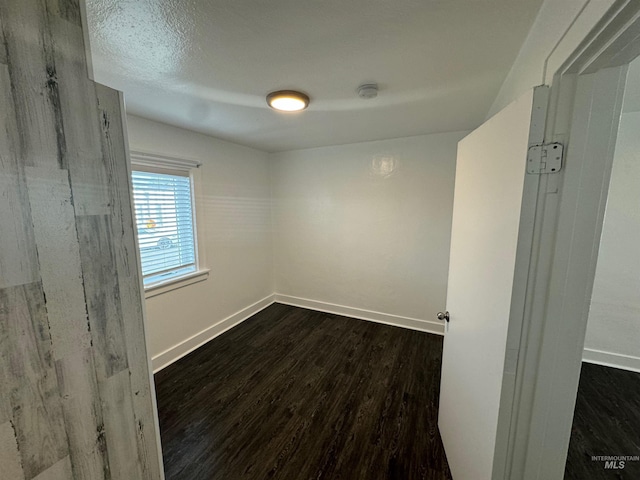 spare room featuring a textured ceiling and dark hardwood / wood-style flooring