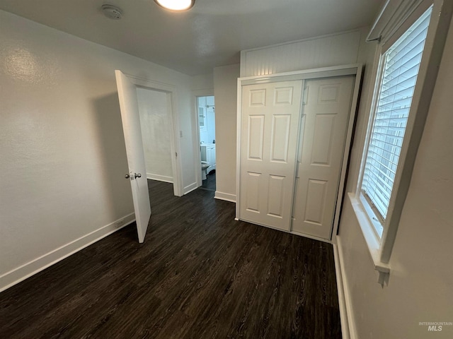 unfurnished bedroom featuring a closet, dark hardwood / wood-style flooring, and multiple windows