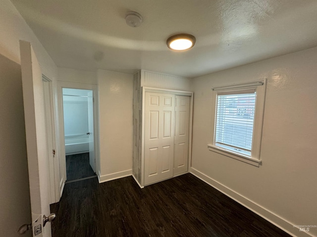 unfurnished bedroom featuring dark hardwood / wood-style flooring and a closet