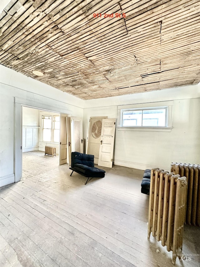 sitting room featuring light hardwood / wood-style floors, radiator heating unit, and brick ceiling