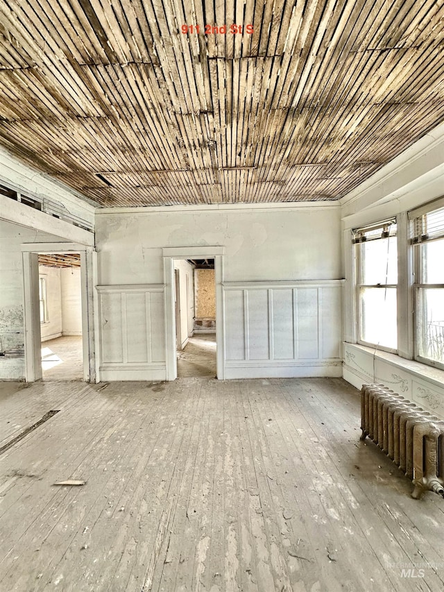 unfurnished room with light wood-type flooring, wood ceiling, and radiator