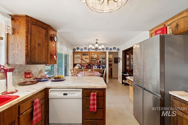 23743 Viking Ln, Wilder, ID 83676 - kitchen with a chandelier, freestanding refrigerator, white dishwasher, a peninsula, and light countertops