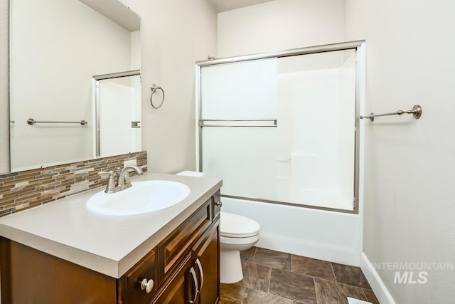 bathroom featuring tasteful backsplash, enclosed tub / shower combo, vanity, and toilet